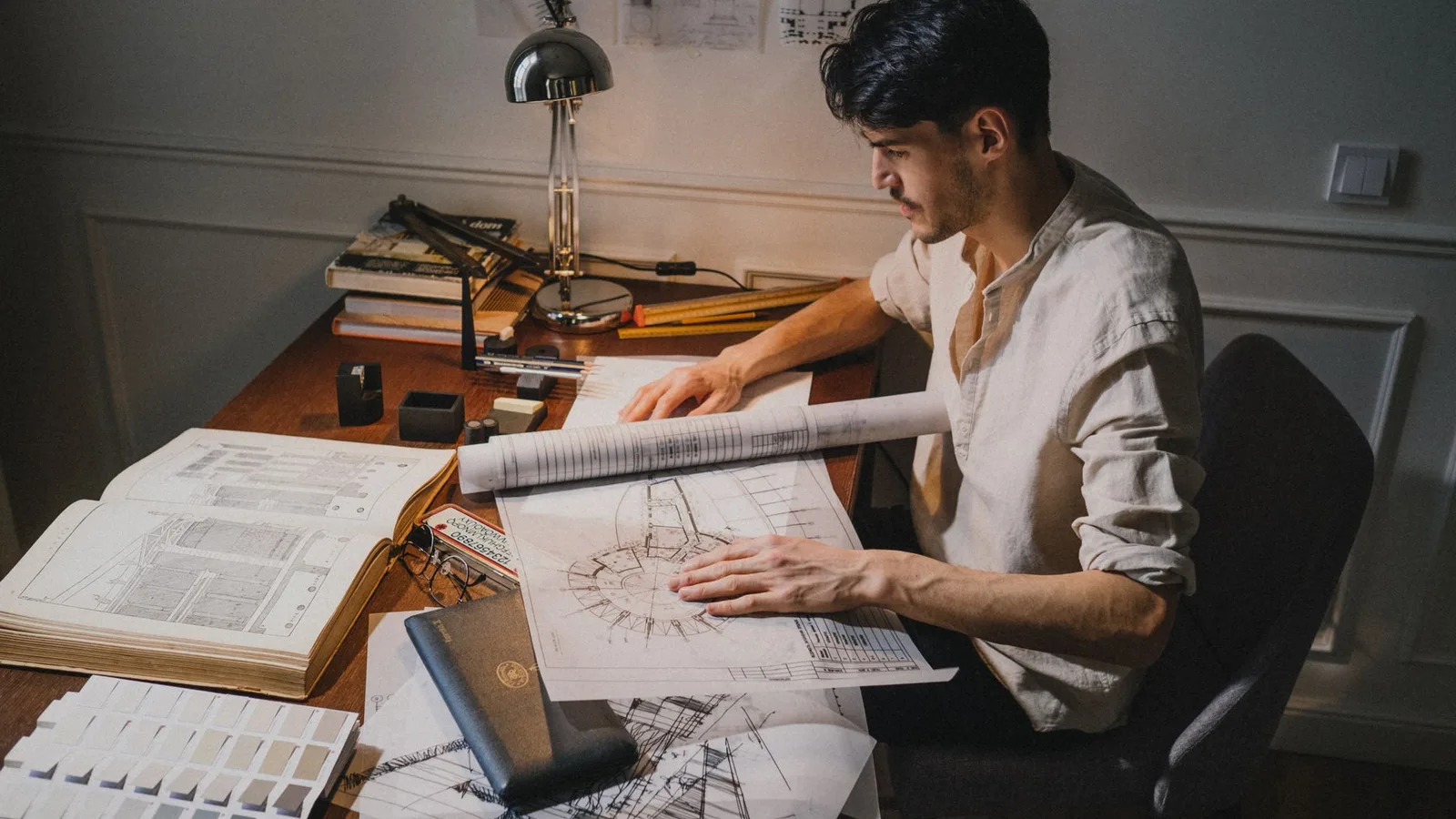 Architecte étudiant des plans et un nuancier de teintes de façade sur sa table de travail